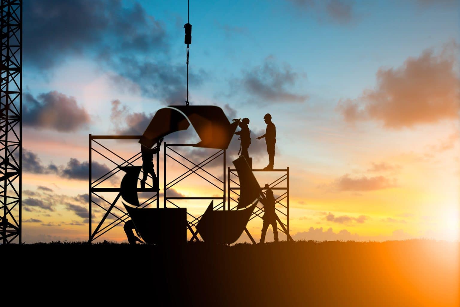 Silhouette of construction workers at sunset, building a large recycle symbol